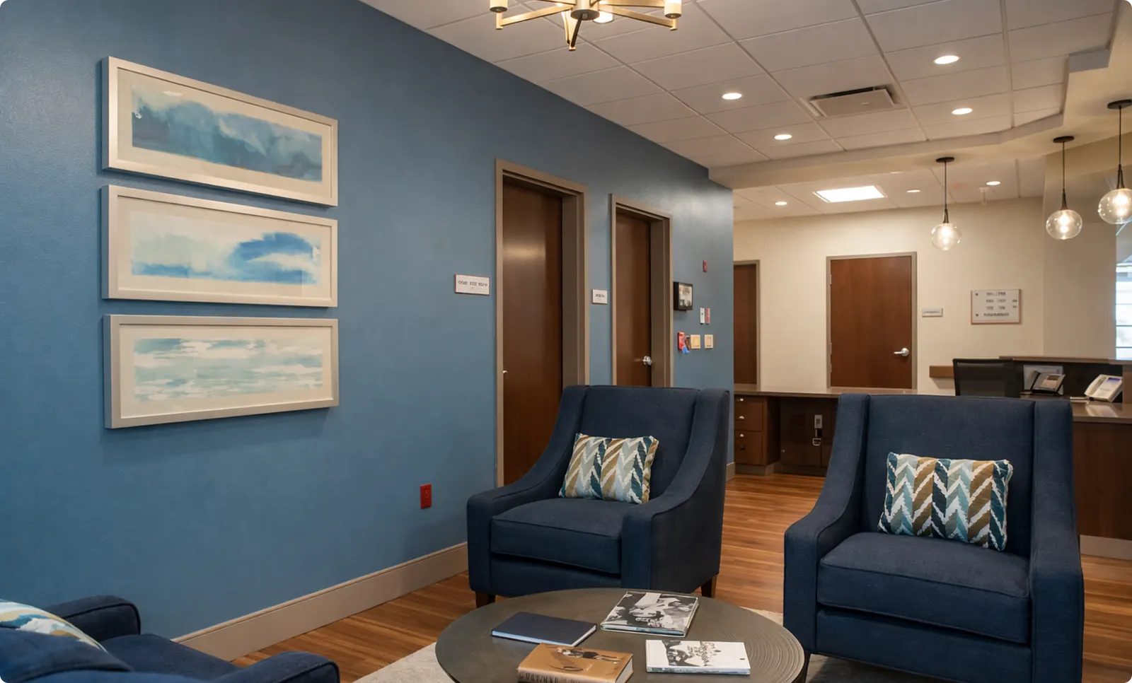 A lounge at Buena Vista with two armchairs, a low table and framed artwork, beside the case management desk