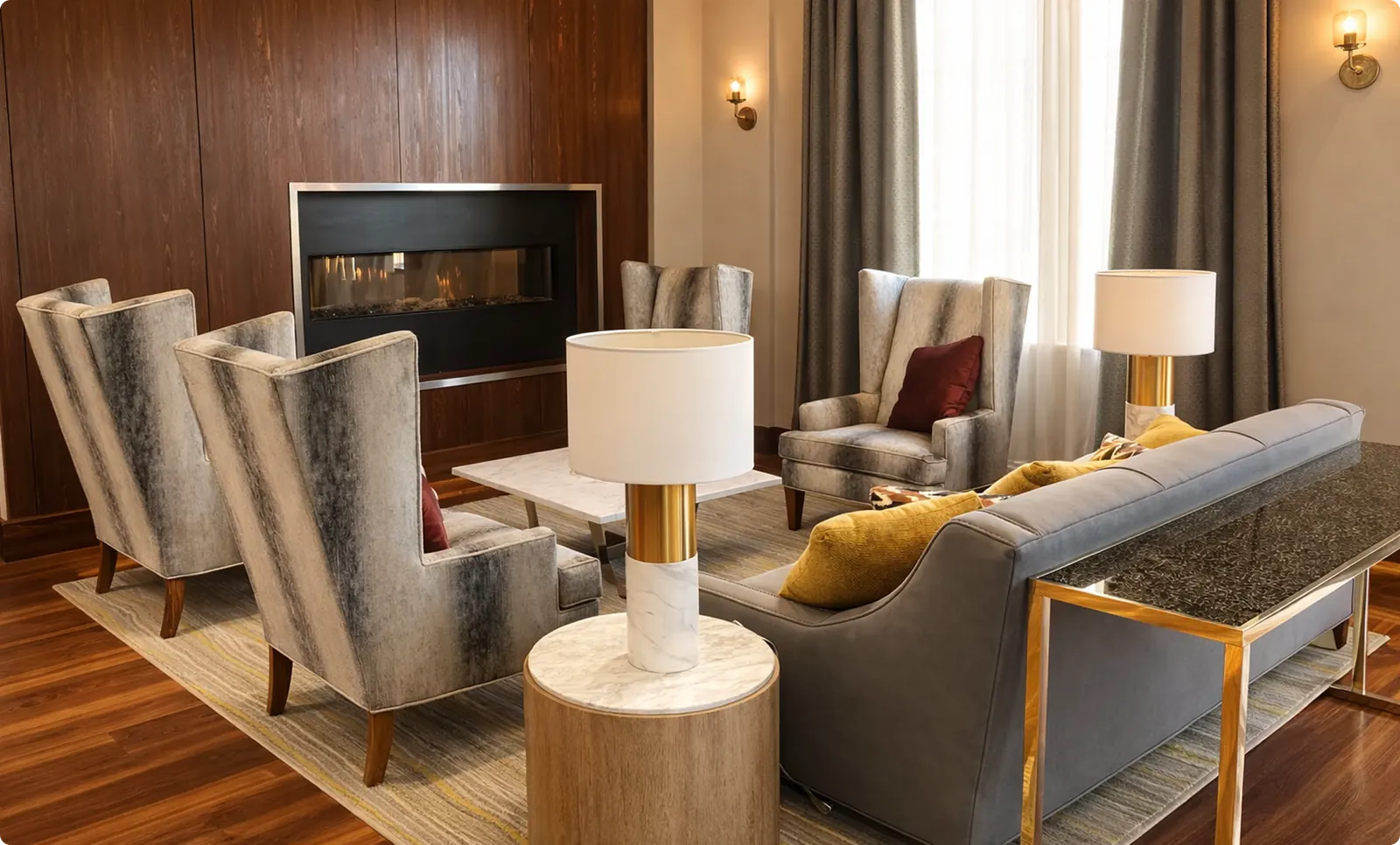 A fireplace gathering area with high-back chairs, sofas and table lamps