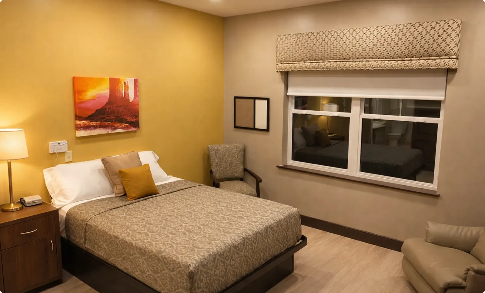 A private bedroom with an upholstered bed, reading chair and large window