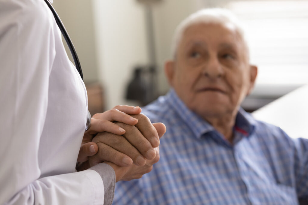 Compassionate female doctor nurse supporting consoling aged retired man patient