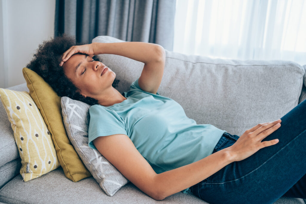 Woman with low energy laying on the couch at home.