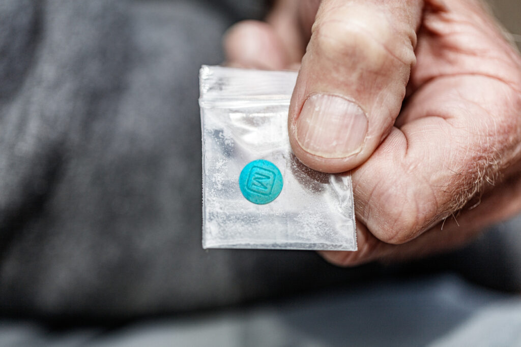 M 30 fentanyl pill opiate in plastic bag in hand close-up